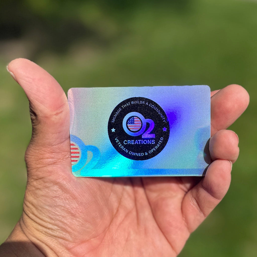 A hand holding a holographic business card with a colorful, eye-catching design.