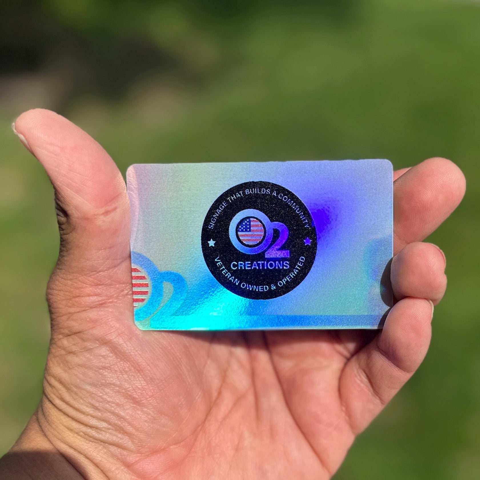 A hand holding a holographic business card with a colorful, eye-catching design.