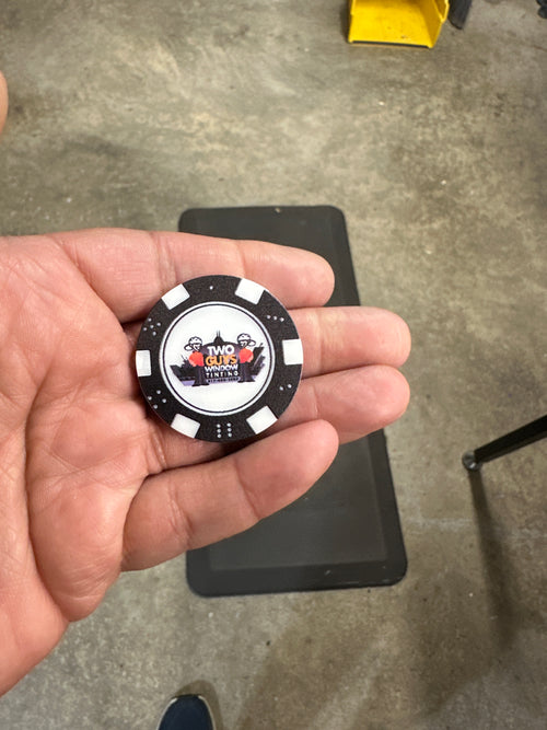 Hand holding a poker chip with a logo on a concrete floor background