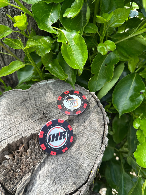 Two poker chips with logos on a wooden log surrounded by green leaves.